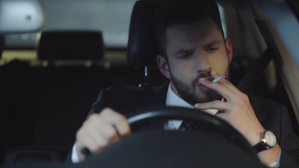 селективное внимание привлекательного мужчины в костюме, курящего во время вождения автомобиля
  - Кадры, видео