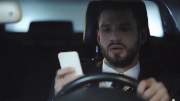 enfoque selectivo del hombre guapo que conduce el coche y el uso de teléfono inteligente
  - Metraje, vídeo