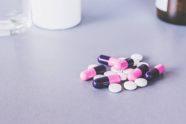pink black and white capsules pills on table - Фото, зображення