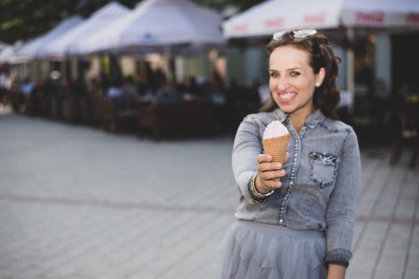 Woman holding ice cream cone towards camera - Fotografie, Obrázek