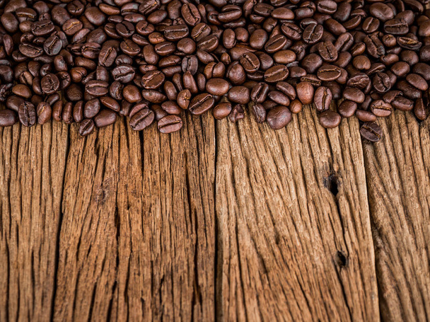 木製のテーブル表面に茶色の焙煎コーヒー豆、コピースペース - 写真・画像