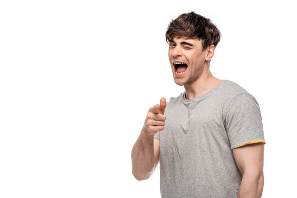 cheerful young man pointing with finger and winking at camera isolated on white - Foto, Imagem