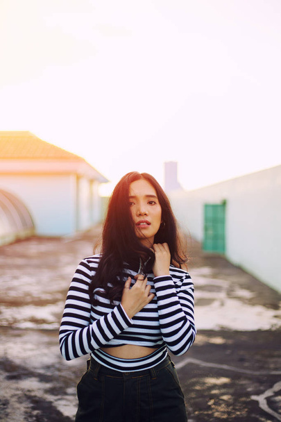 young woman in striped jumper posing in evening sunlight - Foto, Imagem