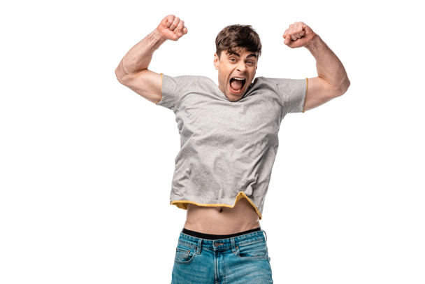 excited young man showing winner gesture while looking at camera isolated on white - Φωτογραφία, εικόνα