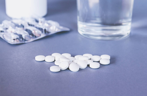 fles-en witte pillen op tafeloppervlak - Foto, afbeelding