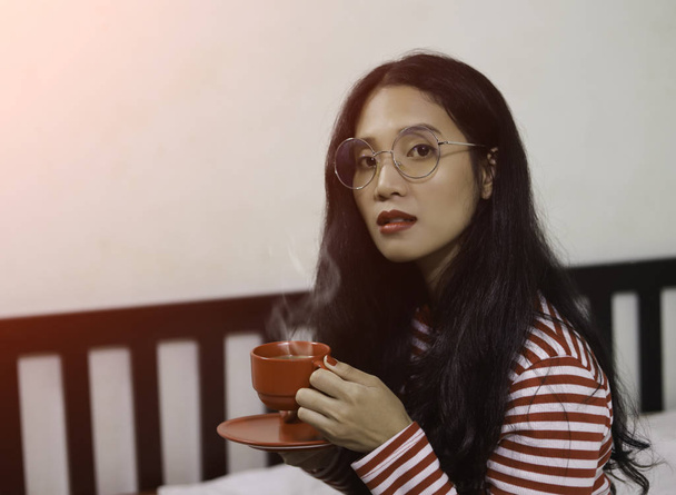 Asiatico donna indossare occhiali holding rosso caffè tazza
 - Foto, immagini