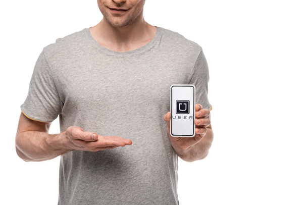 KYIV, UKRAINE - MAY 16, 2019: cropped view of man presenting smartphone with uber app, isolated on white - Foto, Imagen