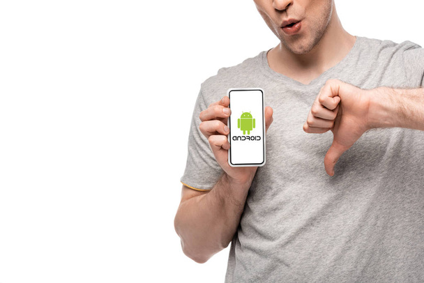 KYIV, UKRAINE - MAY 16, 2019: cropped view of man showing thumb down and smartphone with airbnb app, isolated on white - Photo, image