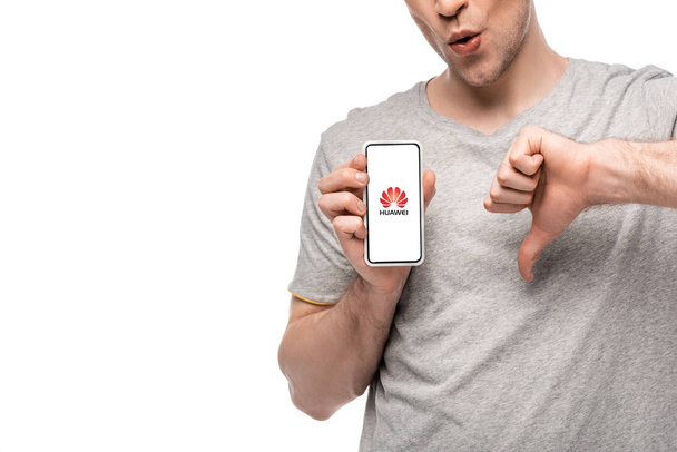 KYIV, UKRAINE - MAY 16, 2019: cropped view of man showing thumb down and smartphone with huawei app, isolated on white - Photo, image