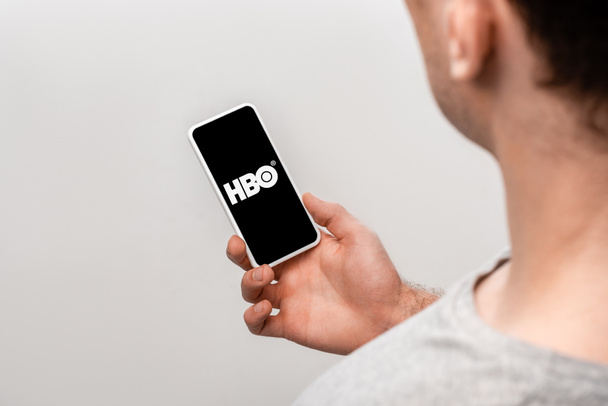 KYIV, UKRAINE - MAY 16, 2019: cropped view of man using smartphone with HBO app, isolated on grey - Photo, Image