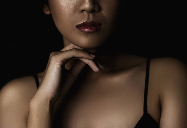 κομμένη βολή της νεαρής γυναίκας με γυαλιστερό δέρμα σε σκούρο φόντο - Φωτογραφία, εικόνα