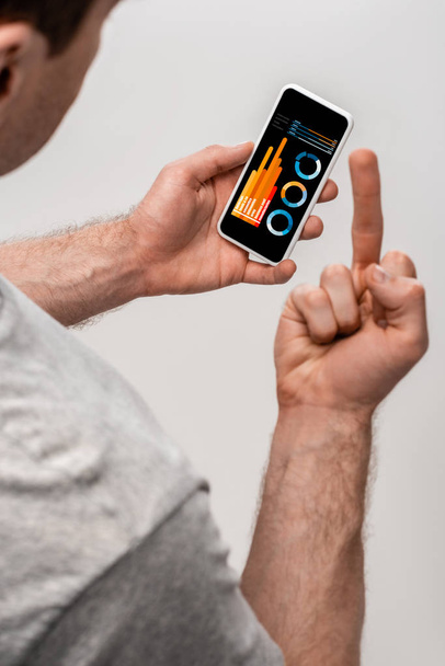 levágott kilátás ember használ smartphone-val infographic app és bemutatás középső ujj, elszigetelt-ra szürke - Fotó, kép