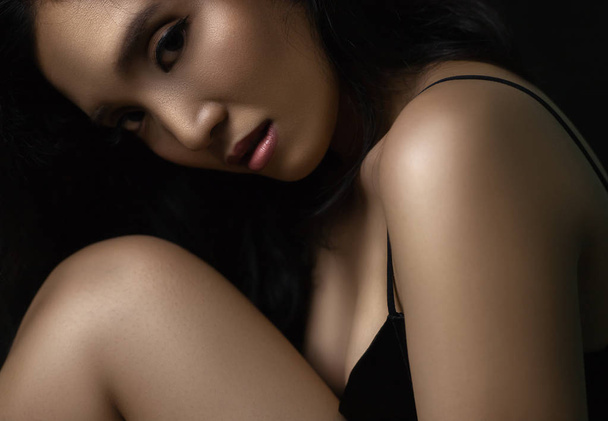 Portret młodej azjatyckiej kobiety z błyszczącą skórą na ciemnym tle - Zdjęcie, obraz