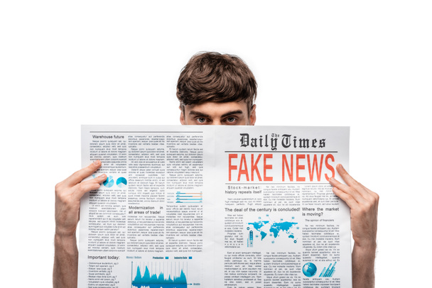 young man looking at camera while holding newspaper with gake news isolated on white - Photo, Image