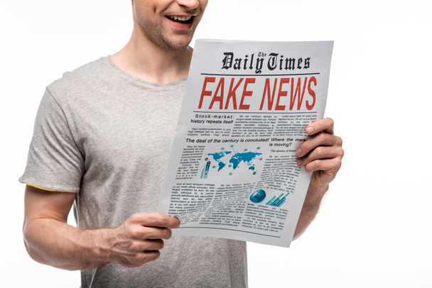 vista parziale del giovane sorridente che legge giornale con fake news isolate sul bianco
 - Foto, immagini