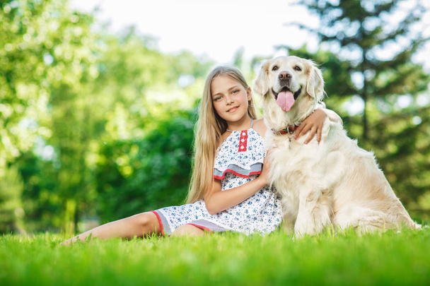 Niña con perro golden retriever en el parque
 - Foto, Imagen