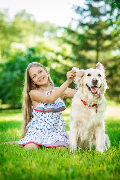 Niña con perro golden retriever en el parque
 - Foto, imagen