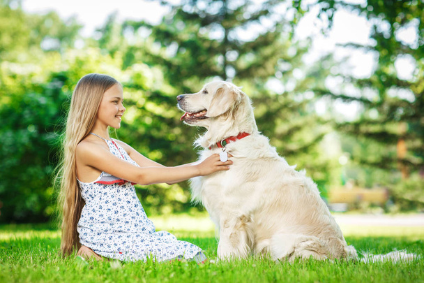 Little girl with golden retriever dog in the park - Photo, Image