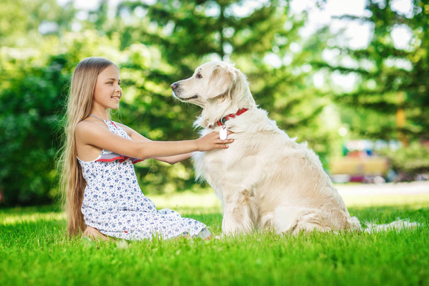 Niña con perro golden retriever en el parque
 - Foto, imagen