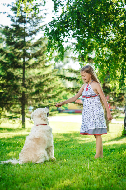 公園でゴールデンレトリバー犬と小さな女の子 - 写真・画像