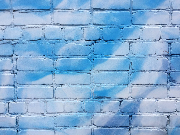 Een oude bakstenen muur is geschilderd blauw en wit, kan worden gebruikt in het interieur of als achtergrond. Abstracte tekening. - Foto, afbeelding