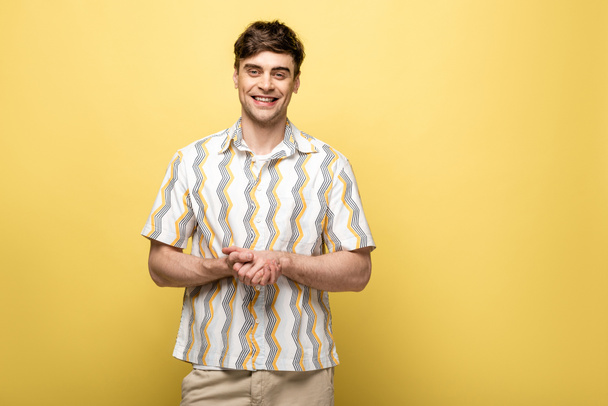 handsome young man in casual clothes smiling at camera on yellow background - Fotoğraf, Görsel