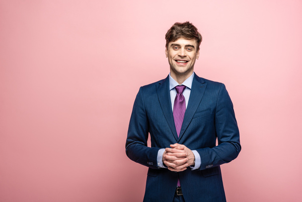 cheerful businessman in suit smiling at camera on pink background - Fotografie, Obrázek