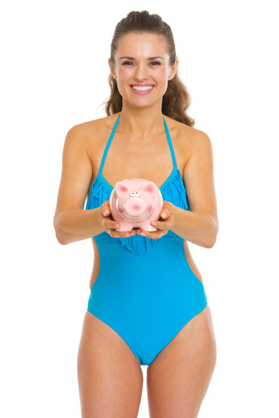 Happy young woman in swimsuit giving piggy bank - Foto, Imagem