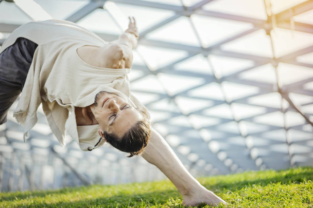 Close up of attractive athletic man practicing yoga and warming up outdoors. - Fotoğraf, Görsel