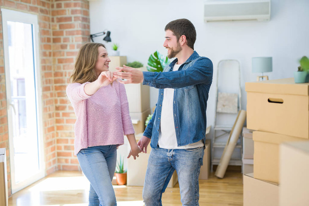 Young couple dancing celebrating moving to new apartment around cardboard boxes - Photo, Image