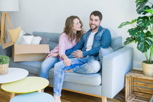Jeune couple amoureux étreignant assis sur le canapé très heureux de déménager dans une nouvelle maison
 - Photo, image