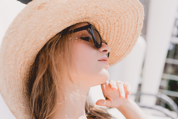portrait of attractive dreamy blonde woman sunbathing in sunglasses and straw hat - Foto, afbeelding