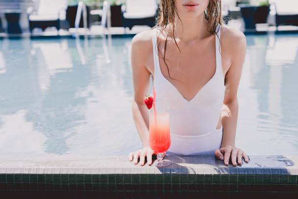 cropped view of wet woman in swimming pool with cool strawberry cocktail - Photo, Image