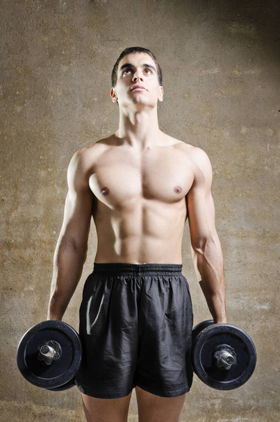 Joven hombre entrenando pesas en viejo gimnasio
 - Foto, Imagen