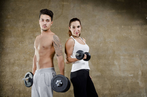 Couple with weights on dirty wall background - Zdjęcie, obraz