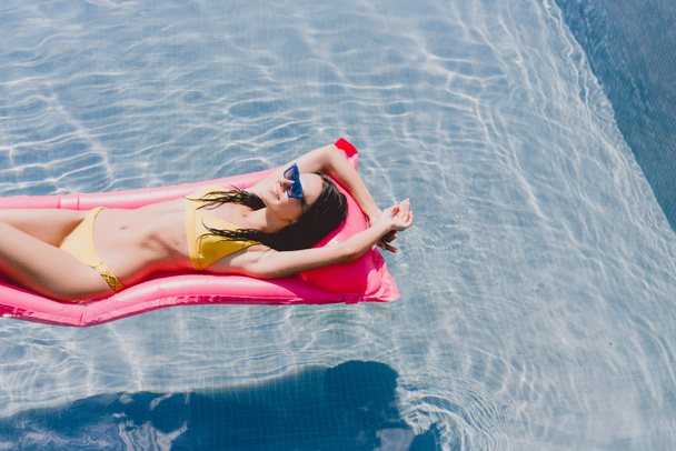 sexy happy brunette woman swimming on pink pool float on clear water - Photo, Image