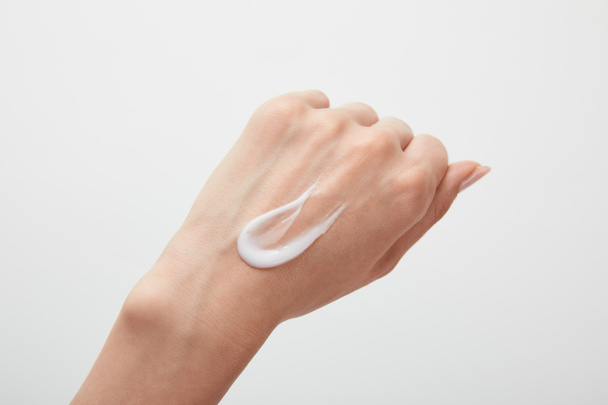 περικομμένη όψη του χεριού της γυναίκας με κρέμα στο δέρμα που απομονώνεται σε λευκό - Φωτογραφία, εικόνα