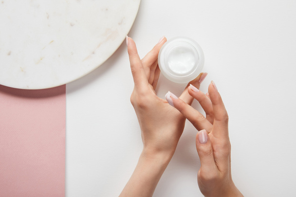 vista recortada de la mujer celebración de la crema en frasco, la aplicación de cosméticos en la piel
 - Foto, imagen