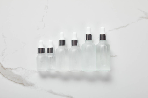 top view of cosmetic glass bottles on white surface - Foto, afbeelding