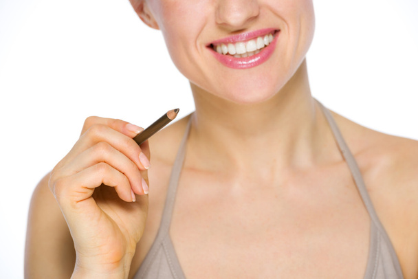 Крупный план улыбающейся молодой женщины, держащей коричневый глаз лайнер
 - Фото, изображение