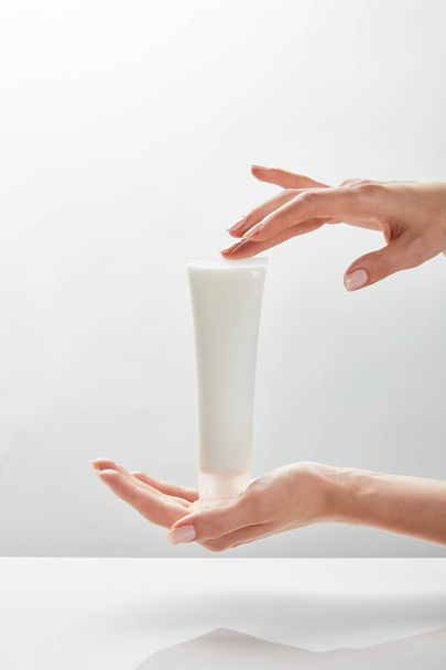 cropped view of woman holding cosmetic cream tube in hands - Fotoğraf, Görsel