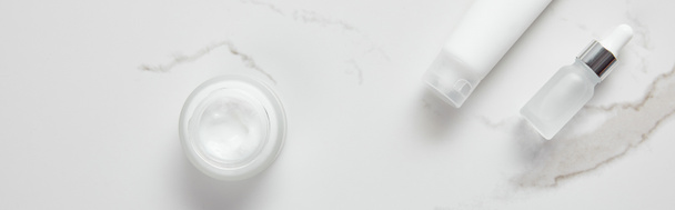 panoramic shot of cosmetic glass bottle, jar with cream and moisturizer tube on white surface - Photo, Image