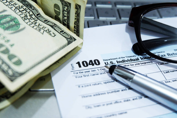税務シーズン:1040米国個人所得税申告フォーム水平上向きのオフィスのラップトップの背景の上のビューは、課税に金属ペンの準備を持つ. - 写真・画像