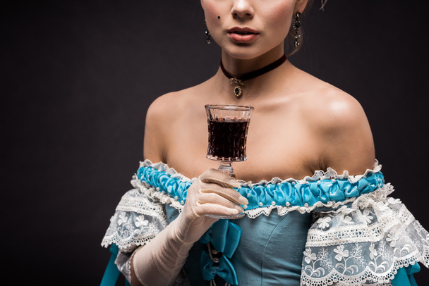 黒いワイングラスを持つビクトリア朝の女性のトリミングされた眺め  - 写真・画像