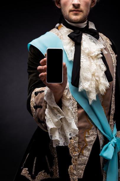 oříznutý pohled na viktoriánský muž držící smartphone s prázdnou obrazovkou na černém  - Fotografie, Obrázek