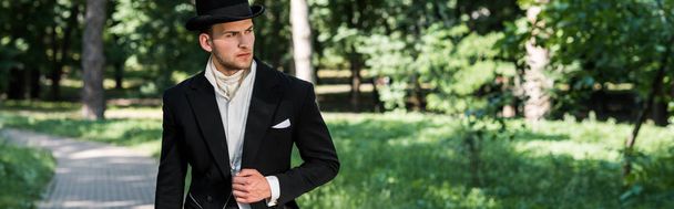 外に立つ帽子をかぶったハンサムなビクトリア朝の男のパノラマショット  - 写真・画像