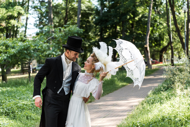 happy victorian man looking at young woman holding umbrella  - Photo, Image