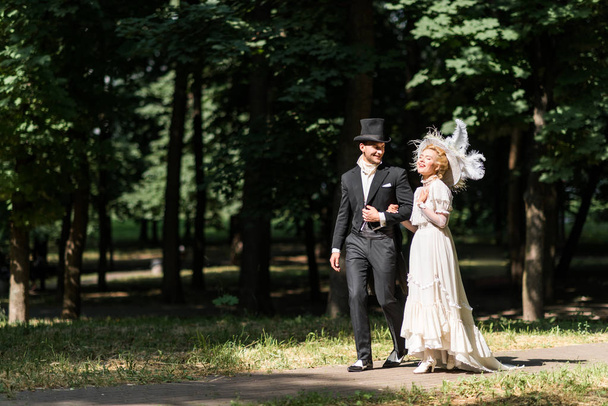 happy young victorian woman and handsome man in hat walking outside  - Foto, Imagem
