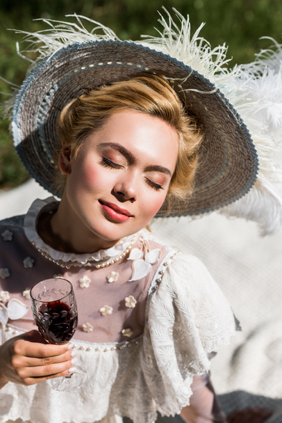 ワイングラスを持つ目を閉じた美しい若いビクトリア朝の女性  - 写真・画像