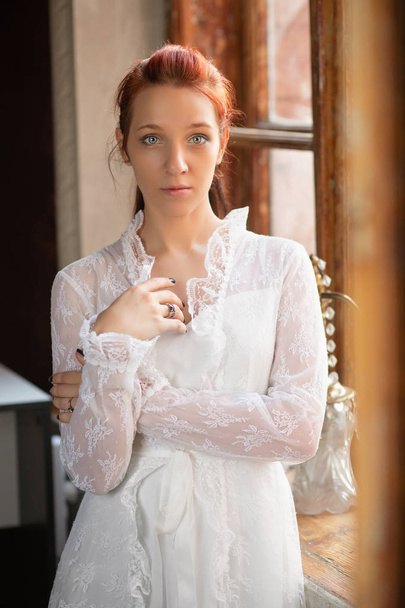 молода леді з рудим волоссям в елегантній білій сукні
 - Фото, зображення